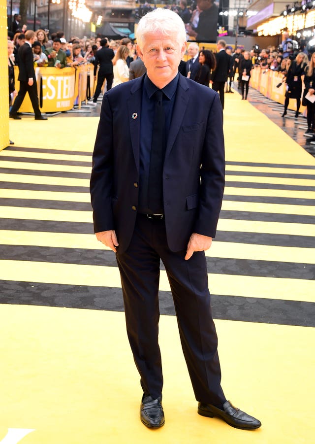 Richard Curtis attending a film premiere dressed in a suit and tie