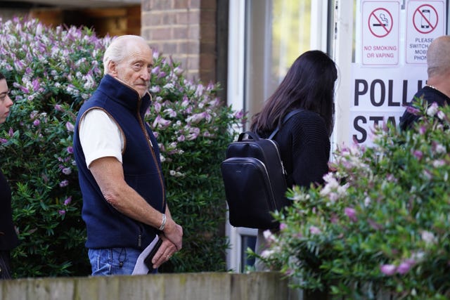 Charles Dance waits in line outside a polling station