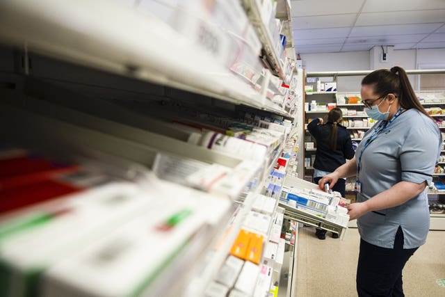 A trainee pharmacy staff member orders medications in drawers and shelves at the Monklands University Hospital, in Aidrie