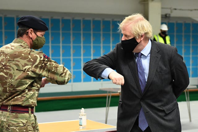 Prime Minister Boris Johnson elbow-bumps a member of the military at a vaccination centre in the Castlemilk district of Glasgow 