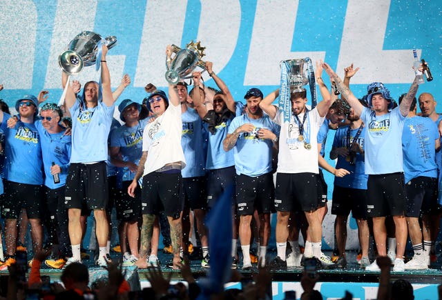 Manchester City players celebrate on stage with their trophies