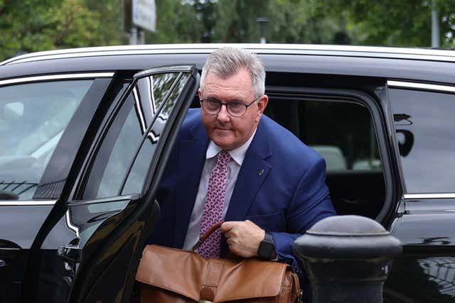 Jeffrey Donaldson exiting a car, holding a brown bag