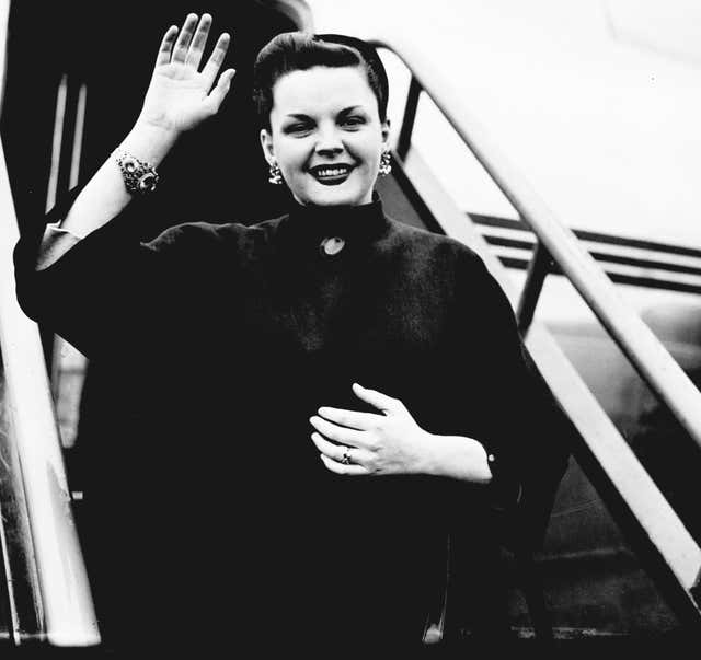 Actress Judy Garland wearing jewelled bracelet and earrings, waves a goodbye as she leaves Northolt Airport for Paris for a holiday after her three weeks’ season at the London Palladium