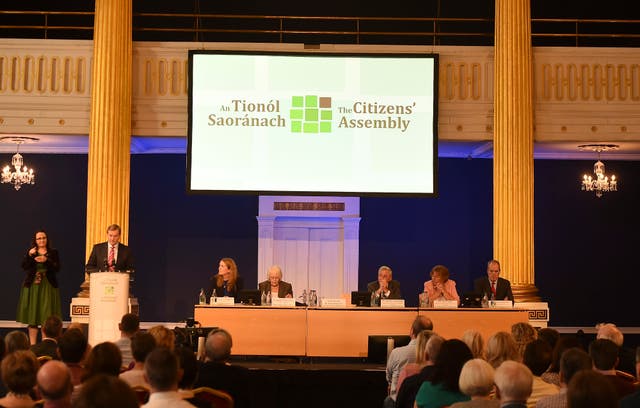 Then-Taoiseach Enda Kenny addresses the Irish Citizens Assembly on legalising abortion. He stands at a lectern on the left of a stage, under a banner with the logo of the Citizens' Assembly