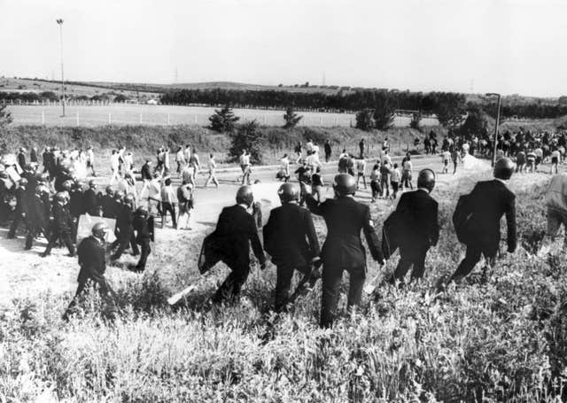 Black and white image of police escorting picketers away from their position near the Orgreave Coking Plant near Rotherham in 1984