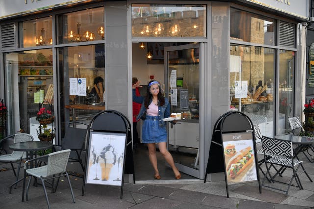 A member of staff carries drinks to customers outside a cafe in Cardiff