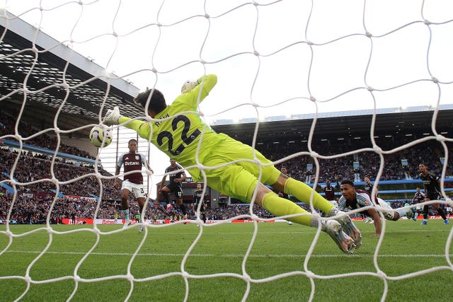 Arsenal goalkeeper David Raya dives to his left to save a header from Aston Villa's Ollie Watkins, right