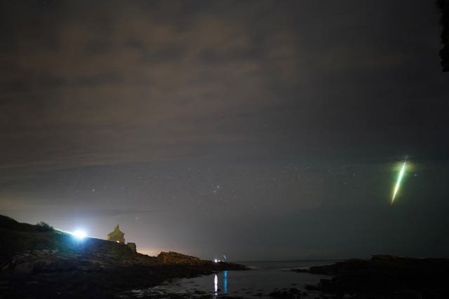 A fisherman watches a meteor during the Draconid meteor shower over Howick rocks in Northumberland