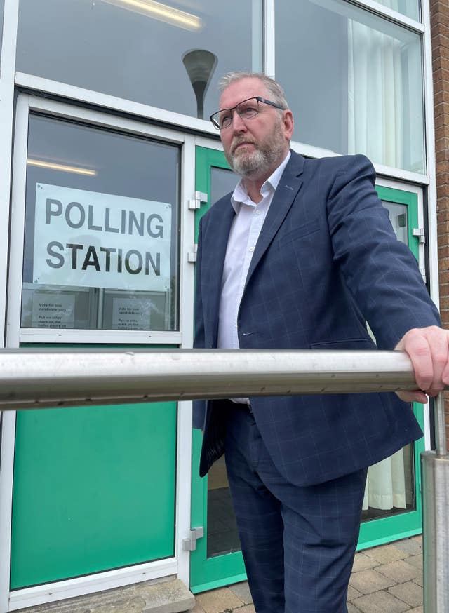 Doug Beattie stands with one hand resting on a railing outside a polling station