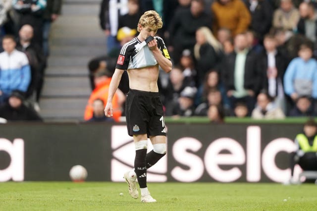 Newcastle’s Anthony Gordon lifts his shirt to his mouth as he leaves the pitch after being shown a red card