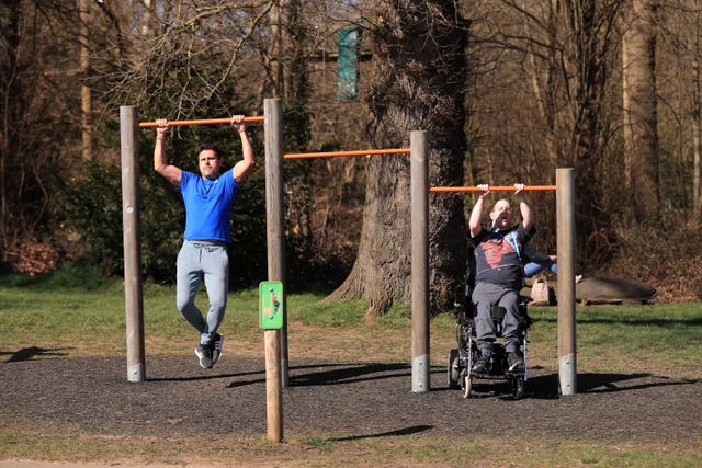 People exercise on outdoor equipment at Stoke Park in Guildford