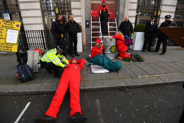 Police officers search an activist outside BP's headquarters