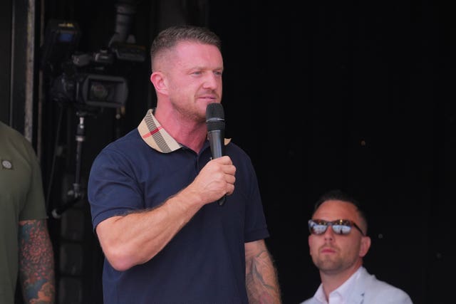 Tommy Robinson holds a microphone and gives a speech