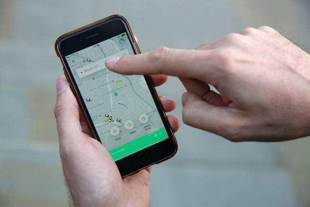 A man using an Uber App on his mobile phone (Matt Alexander/PA) 