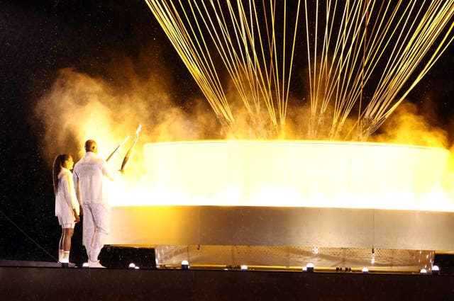 The Olympic flame is lit by Marie-Jose Perec, left, and Teddy Riner at the opening ceremony for the Paris Games