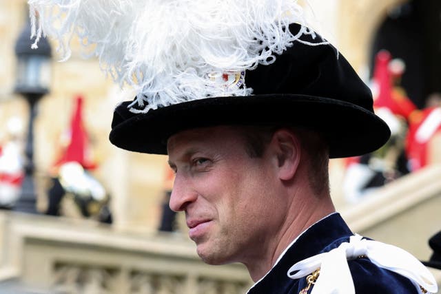 The Prince of Wales smiling while dressed in Order of the Garter hat and robes