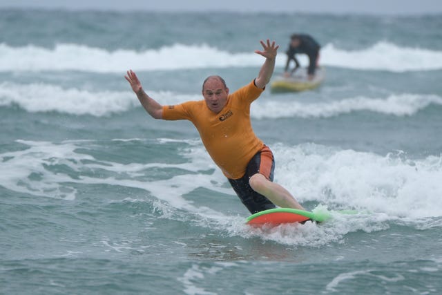 Sir Ed Davey tries - and fails - to ride a surfboard standing up