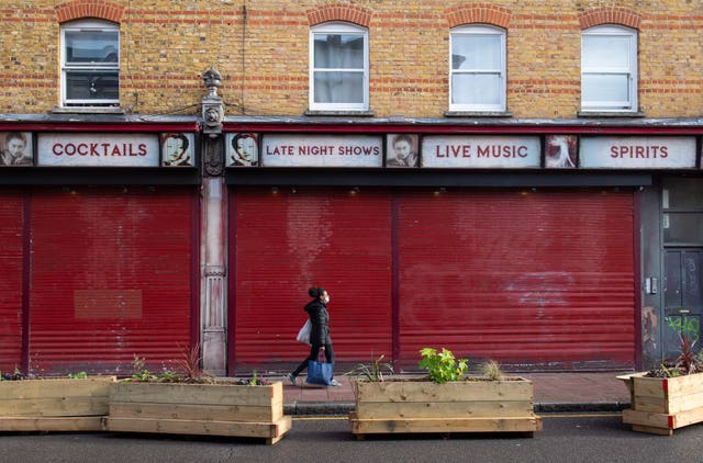 A woman passes a shuttered bar in Brixton, south London, at the start of the first full week of the four-week national lockdown in England (Dominic Lipinski/PA)