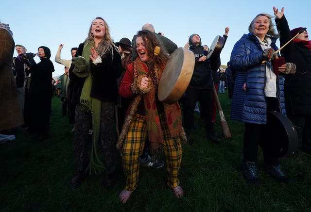 People celebrate the sun rising as they gather for the winter solstice at Newgrange, Co Meath