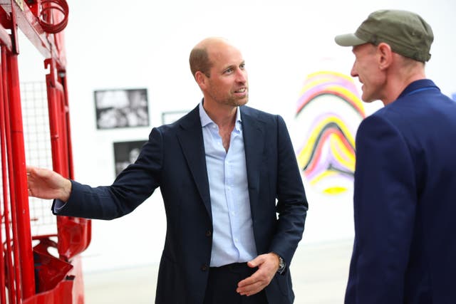 The Prince of Wales speaks to a man in a cap