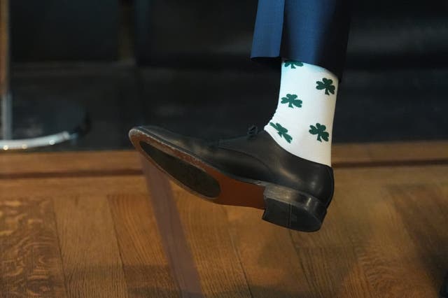 A man's foot, wearing socks decorated with green Shamrocks