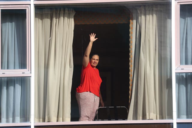 A hotel guest waves to members of the media from the window of Radisson Blu Edwardian Hotel