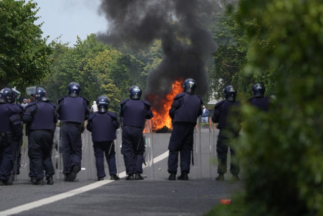 Black-clad officers watch a fire