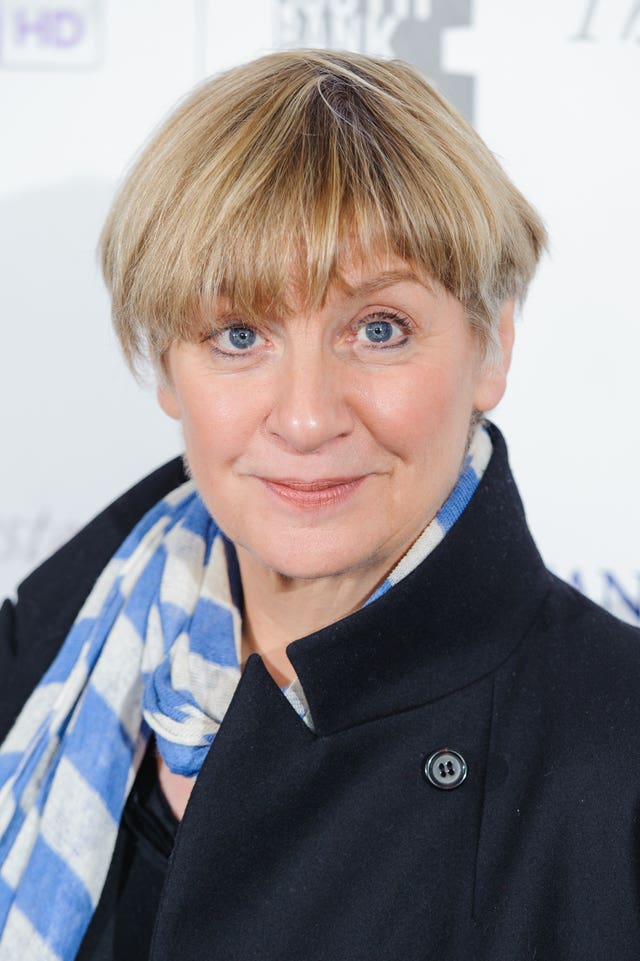 Victoria Wood wearing a blue and white scarf on a red carpet