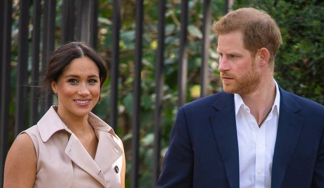 Harry glancing back at Meghan, who smiles directly at the camera