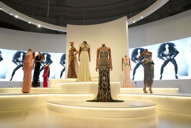 Colourful dresses from Naomi Campbell's career displayed on a stage