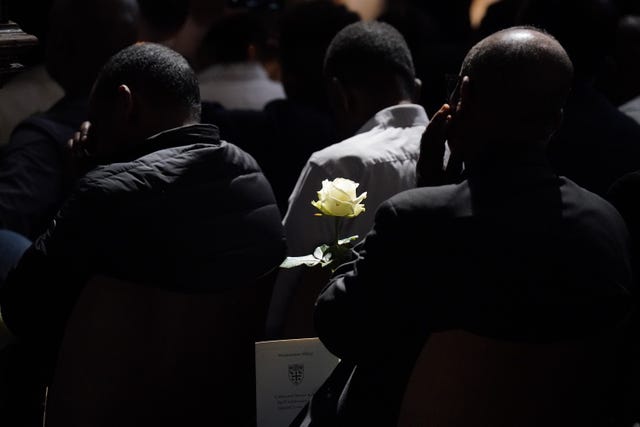 A member of the public holds a white rose at the Grenfell fire memorial service at Westminster Abbey in London
