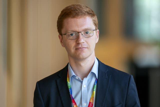 Head and shoulders photo of Ross Greer walking through Parliament