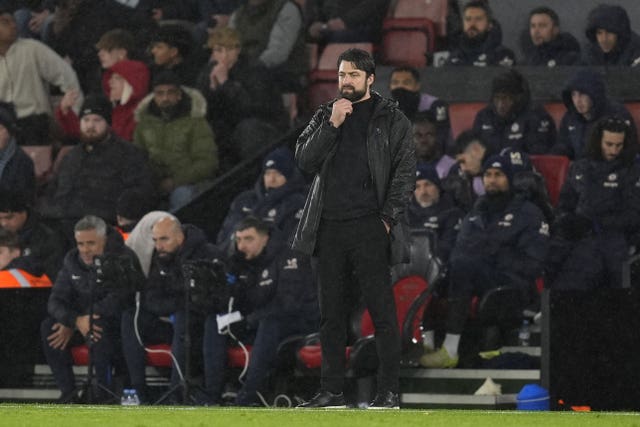 Russell Martin touches his beard with his right hand on the touchline