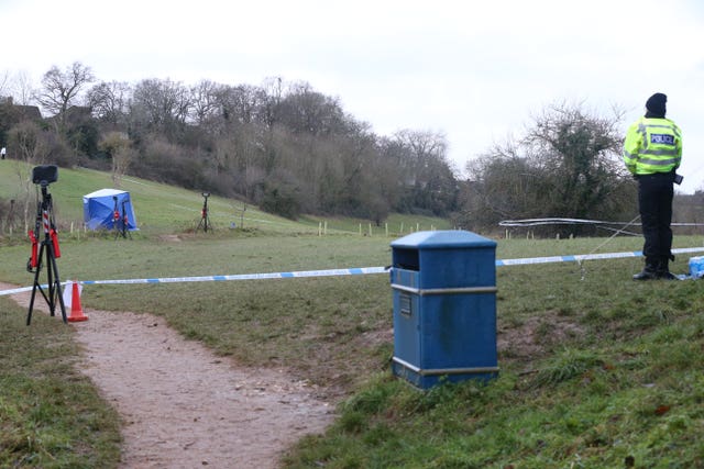 A police officer watches as a forensic tent is set up in Bugs Bottom fields in Emmer Green, Reading