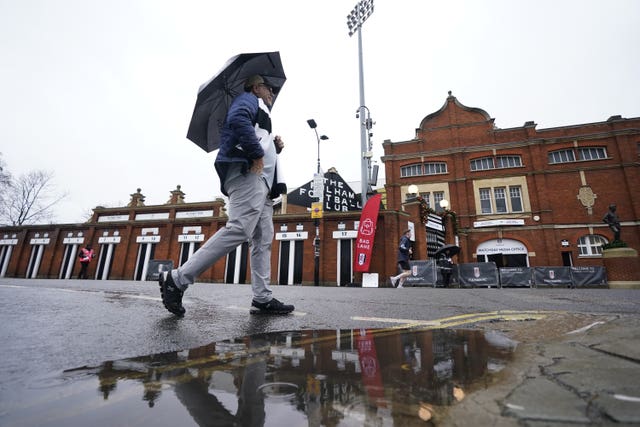 A man with an umbrella walks past a puddle