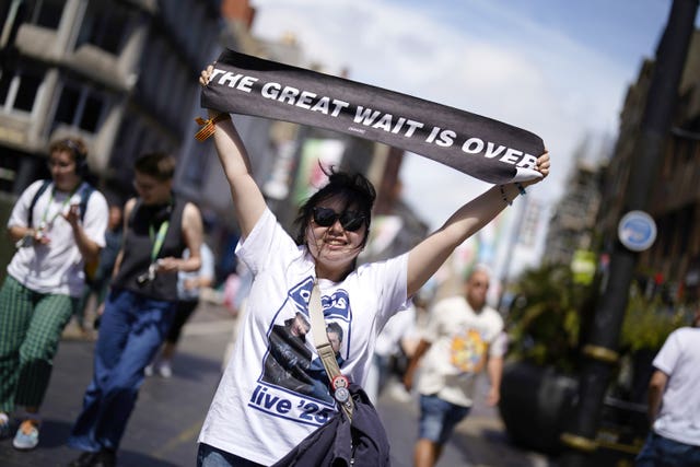 An Oasis fan holding up a banner which reads 'The great wait is over'