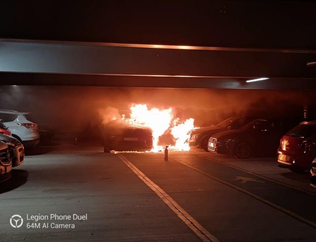 A vehicle on fire in a car park