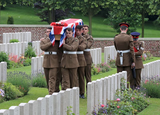 Soldiers carry one of the coffins of two young privates and an unknown soldier, who fought during the First World War, during a burial service at Hermies Hill British Cemetery, near Albert, France