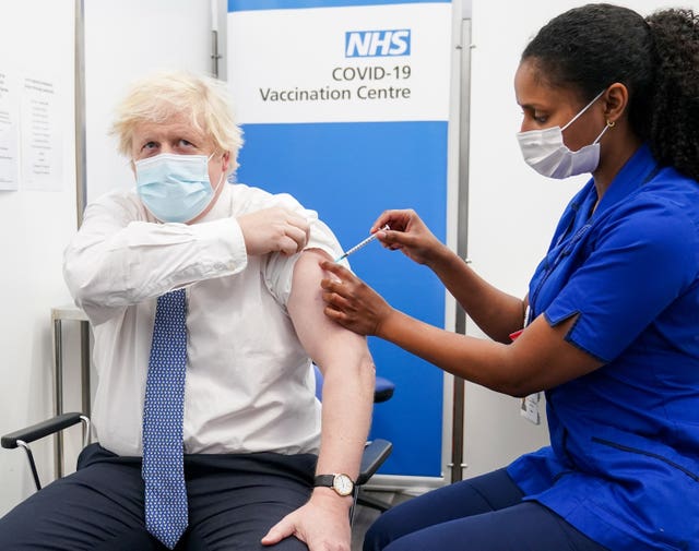 Boris Johnson in a face mask with his sleeve rolled up receives his Covid vaccine booster jab from a nurse, also in a face mask