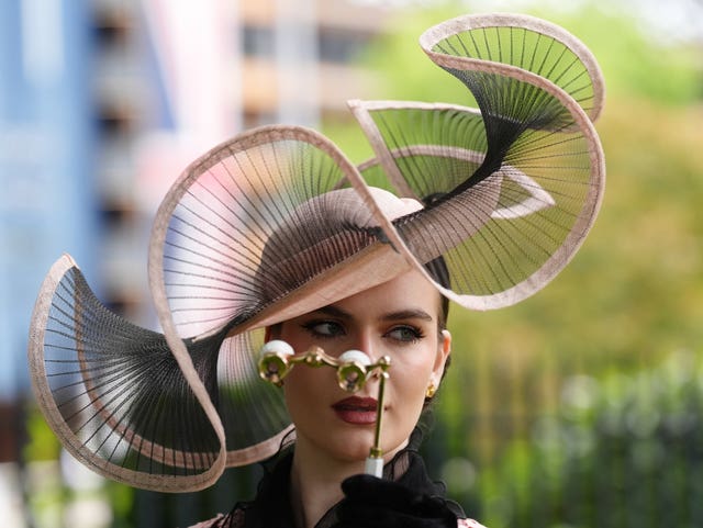 A woman wears a hat while holding a pair od binoculars