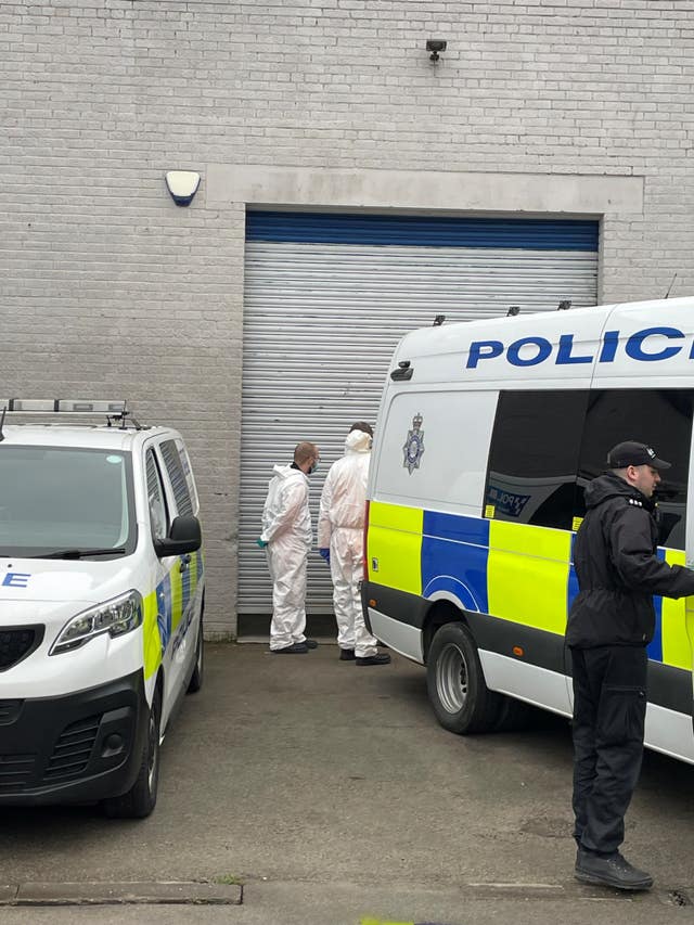 Police officers, scenes of crime officers and police vehicles outside a building