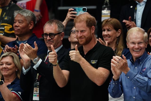 Harry give two thumbs up as he stands next to Dominic Reid who claps as they watch the Invictus wheelchair rugby