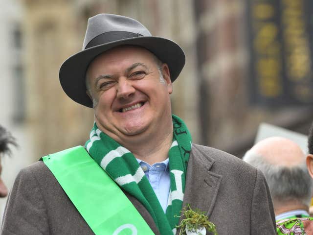 Dara O Briain wearing a green scarf and sash and shamrock