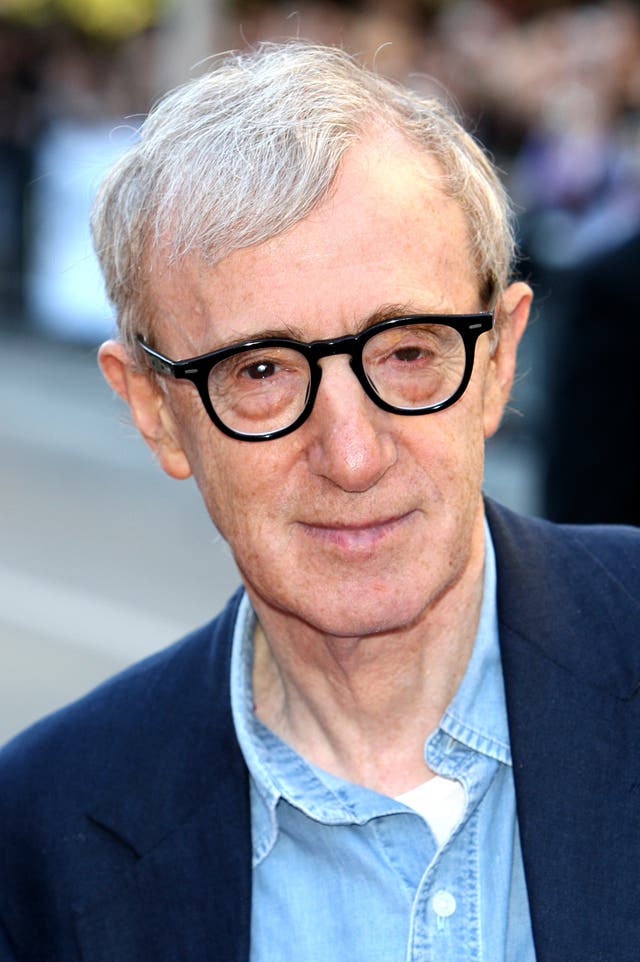 Woody Allen in blue shirt and navy suit jacket and thick-rimmed glasses