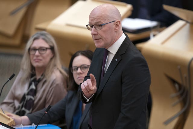 John Swinney standing while speaking in Parliament