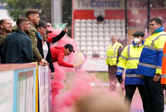 Swindon fans are spoken to by stewards as they throw objects towards the pitch 