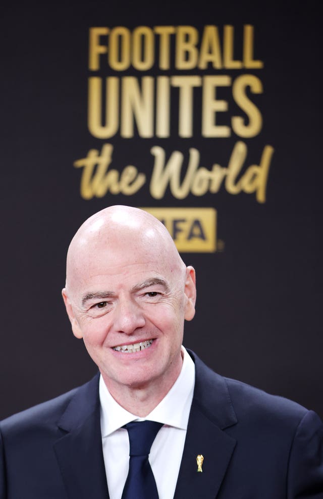FIFA President Gianni Infantino smiles in front of a backdrop reading 'Football unites the world'