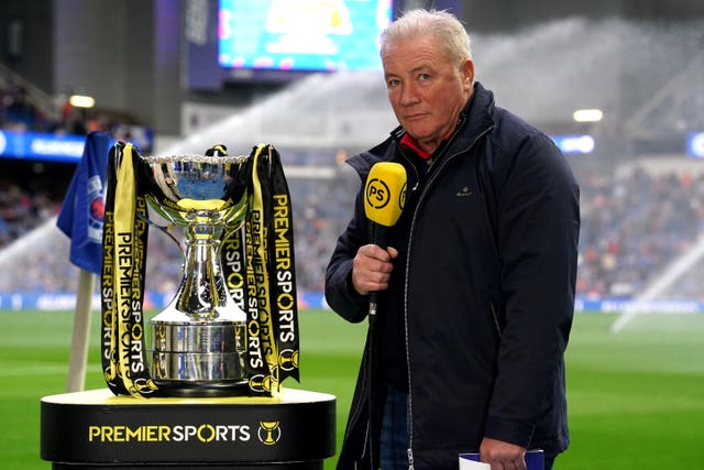 Ally McCoist with a microphone standing next to the Premier Sports Cup