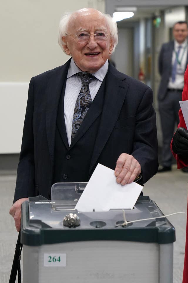 Michael D Higgins smiles as he drops his vote into a ballot box