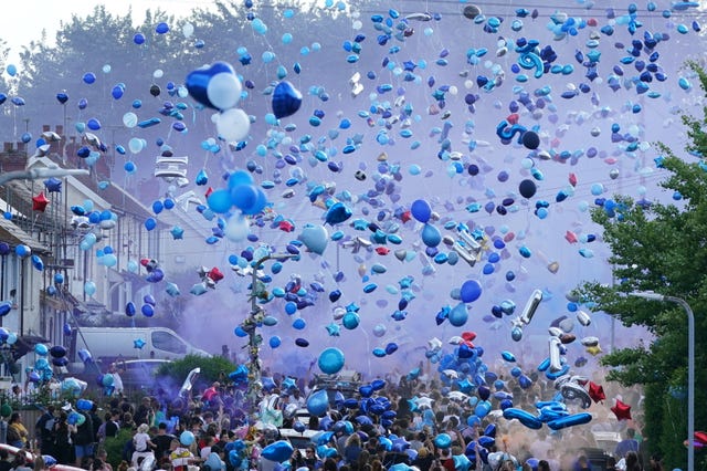 People release balloons during a vigil for the victims of a road traffic collision on Snowden Road in Ely, Cardiff, on Monday